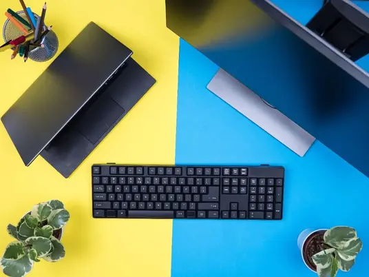 Flat lay of a keyboard placed next to a modern laptop on a desk