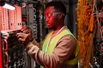Network technician inspecting server racks in a data centre